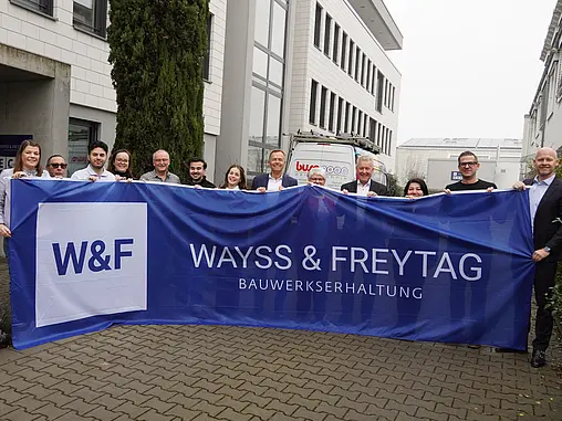 Mehrere Menschen halten eine blaue W&F Flagge hoch.