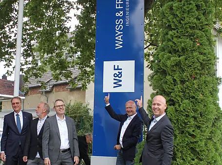 Die Vorstände von Wayss & Freytag stehen vor dem neuen blau-weißen Logo.